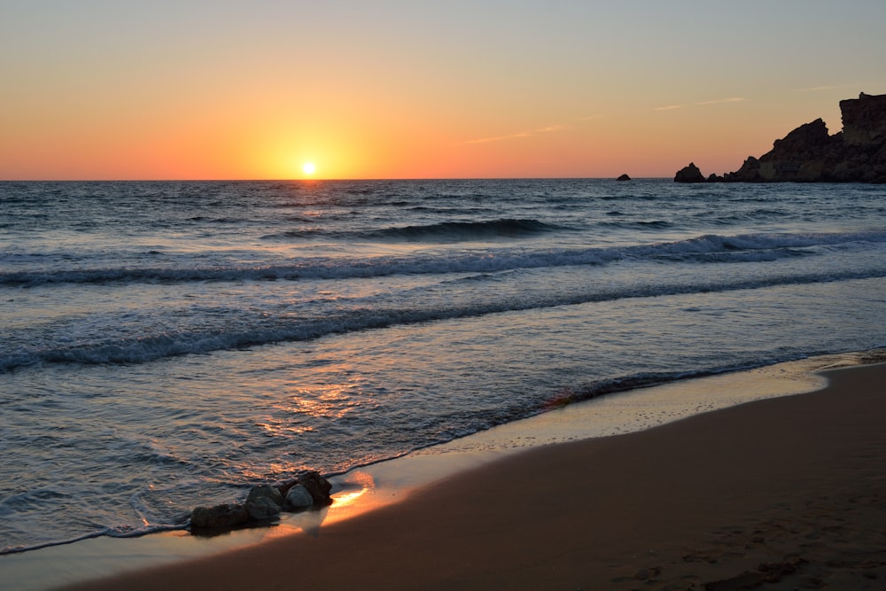 sea waves crashing on shore during sunset