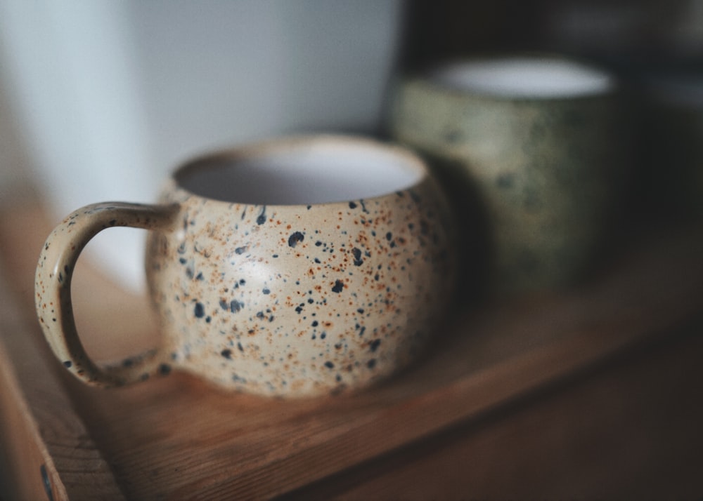 white and blue ceramic mug on brown wooden table