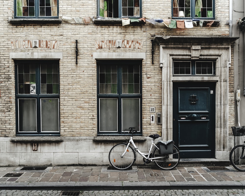 black bicycle parked beside brown brick building