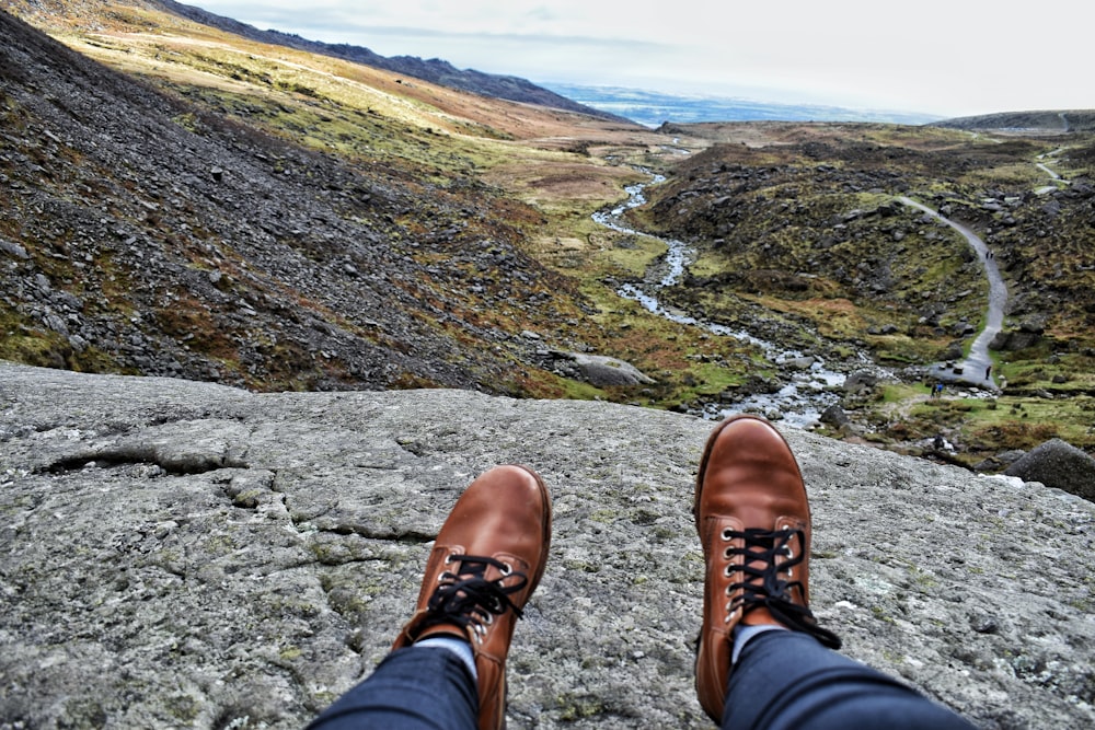 岩の上に座っている茶色の革靴を履いた人