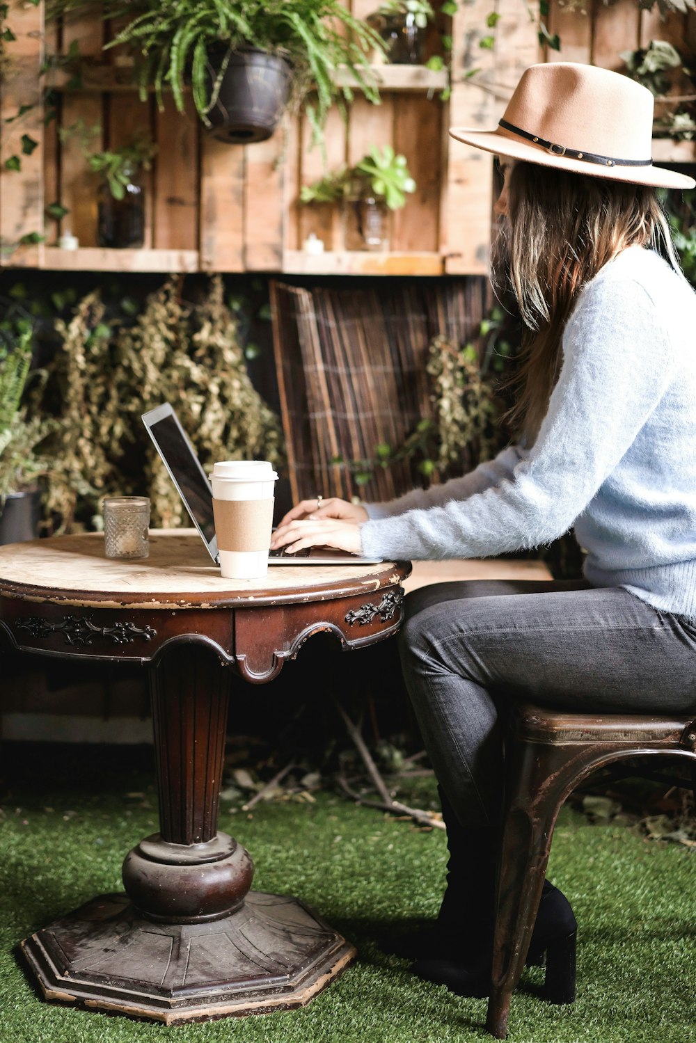 woman in gray sweater sitting on brown wooden table