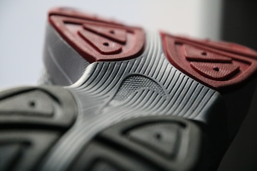 Close-up view of the sole of a shoe, showcasing intricate textures and patterns. The sole features geometric designs with a combination of ridges and grooves.