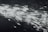 A dynamic burst of light particles streaks across a dark background, creating an abstract and energetic visual effect. The particles appear to be moving at high speed, with varying intensities and sizes, giving the image a sense of motion and depth.