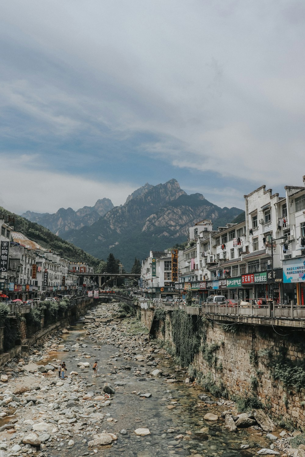 white and brown concrete buildings near mountain under white clouds during daytime