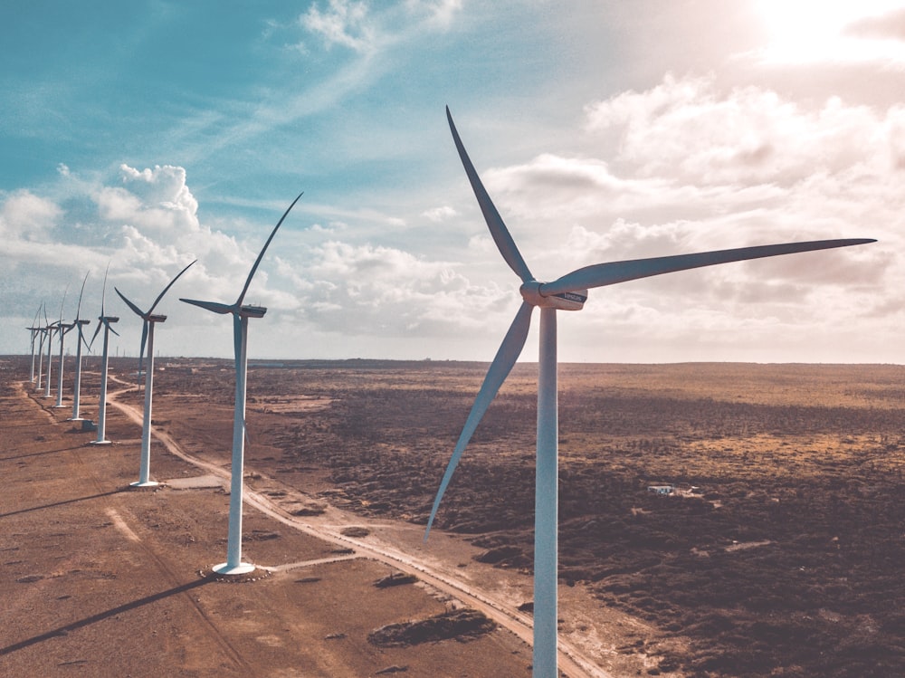 wind turbines on brown sand under white clouds and blue sky during daytime