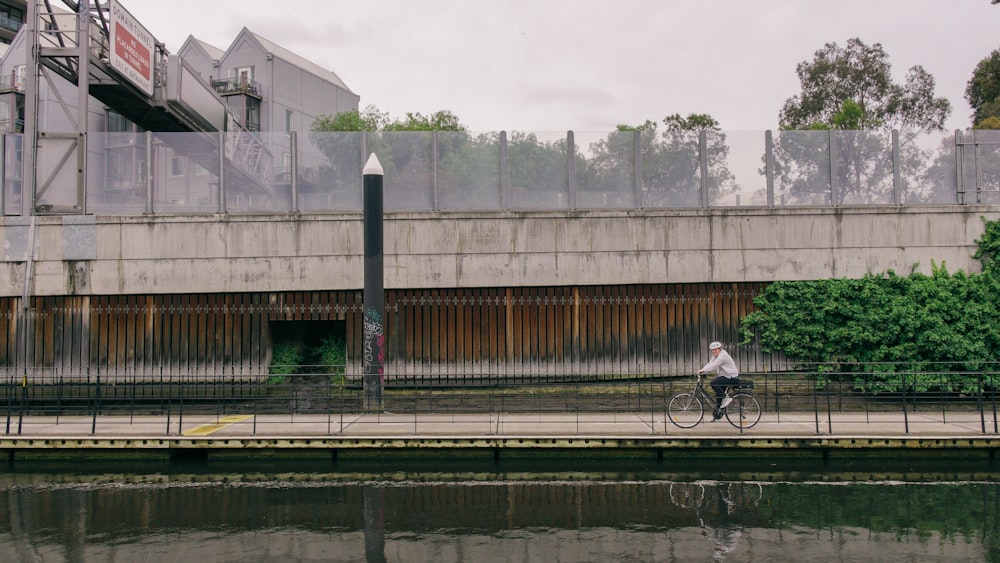 man in black jacket riding bicycle on bridge during daytime