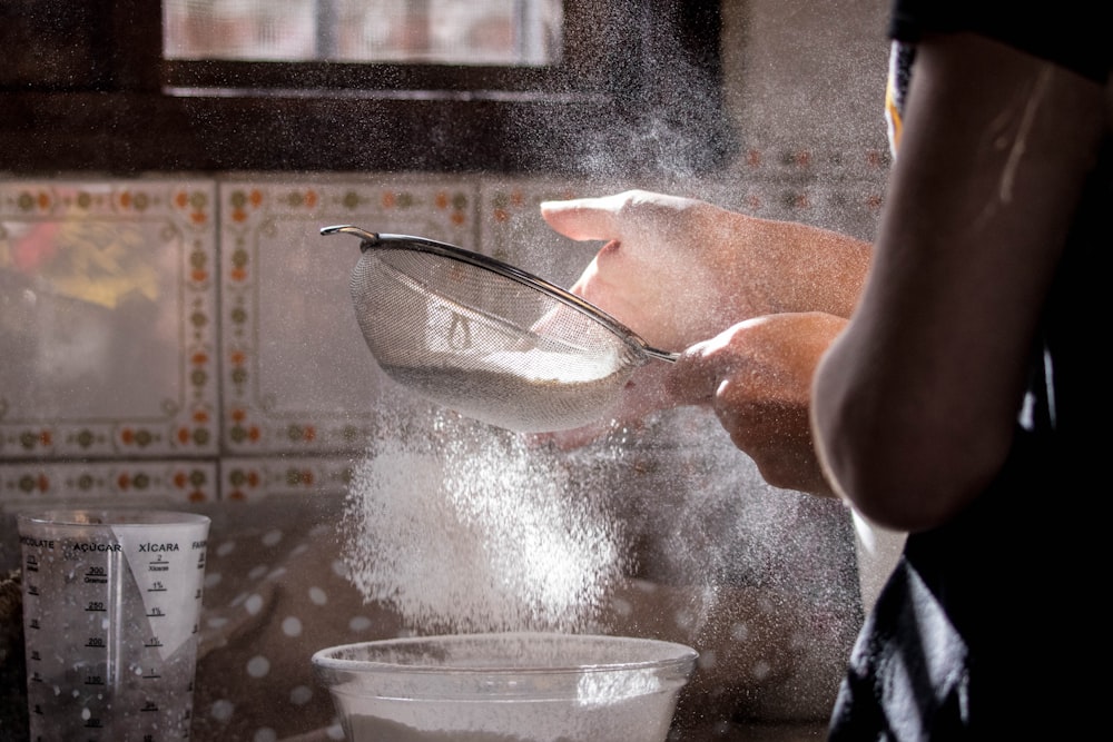 person pouring water on clear glass bowl