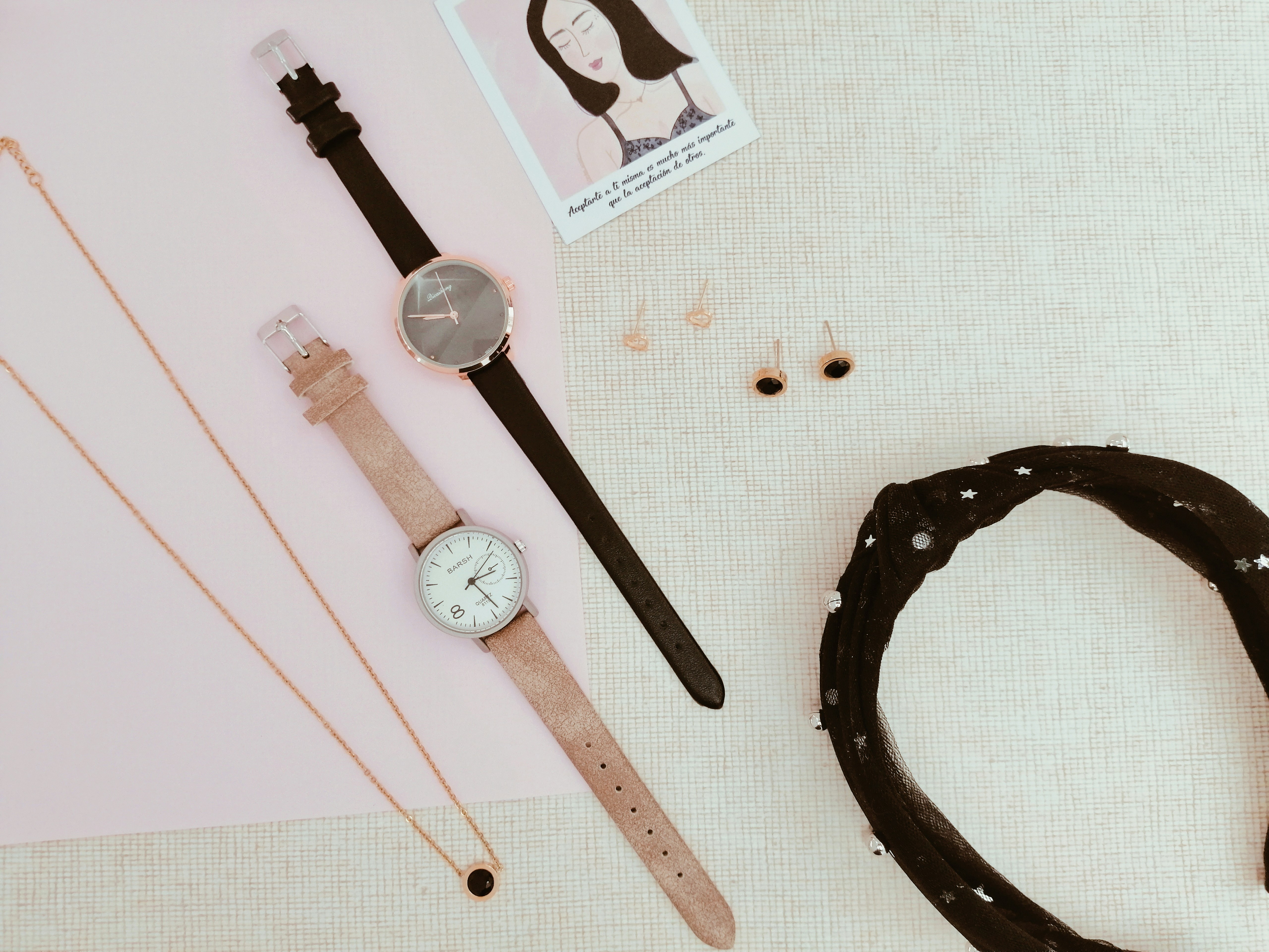Orologi eleganti, gioielli e una fascia per capelli esposti su superfici testurizzate.