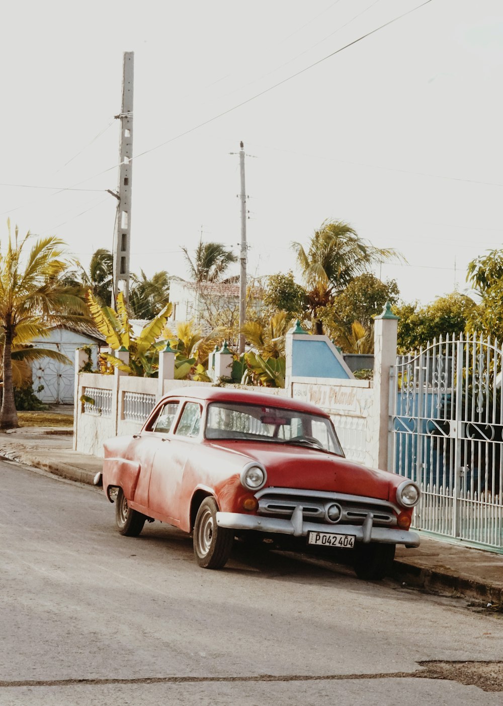 red and white vintage car parked beside white steel fence during daytime