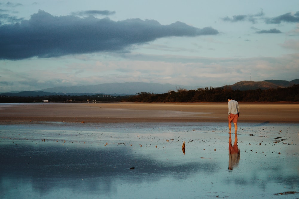 woman in white dress walking on beach during daytime