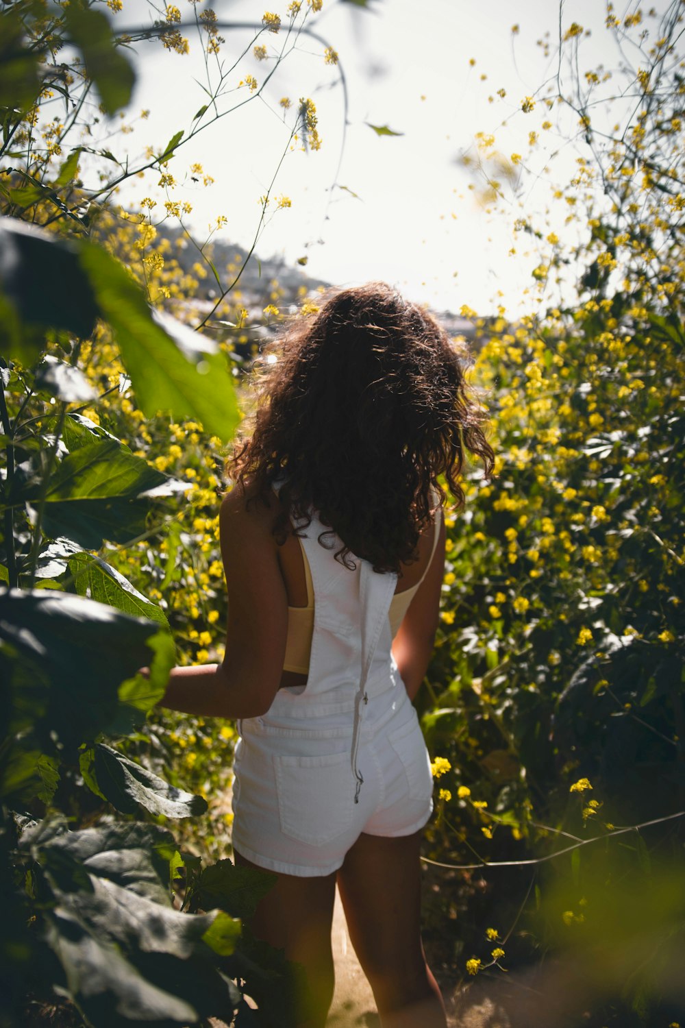 woman in white tank top standing near green leaf tree during daytime