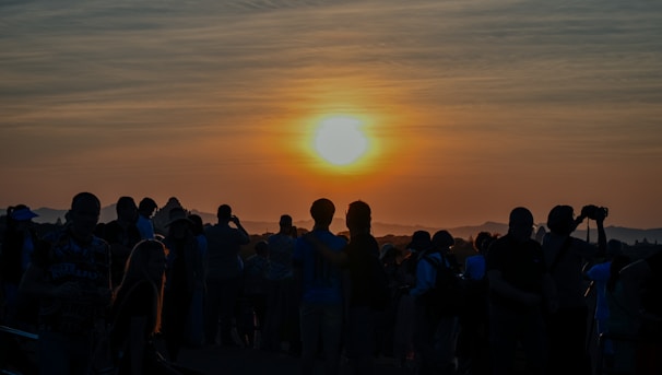 A sunset silhouette of volunteers gathered around a newly constructed house, sharing stories.