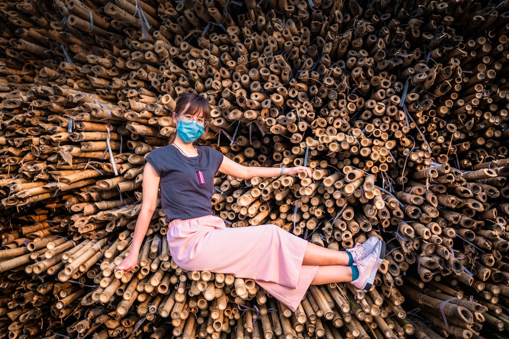 woman in blue t-shirt and pink skirt sitting on brown wood log