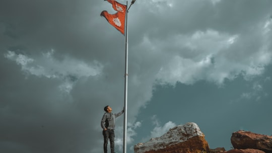 man in black jacket and black pants standing on rock under white clouds during daytime in Chobhar Nepal