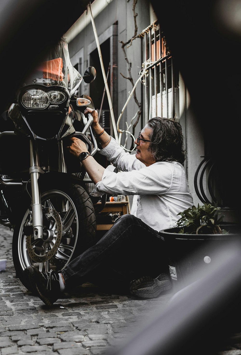 man in white dress shirt and black denim jeans sitting on black motorcycle