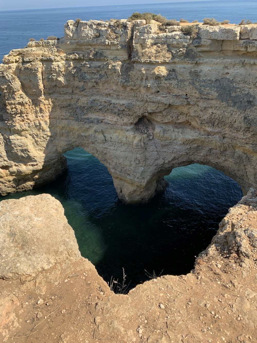 Formación rocosa marrón junto al mar azul durante el día