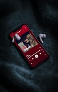 red iphone 5 c on black textile