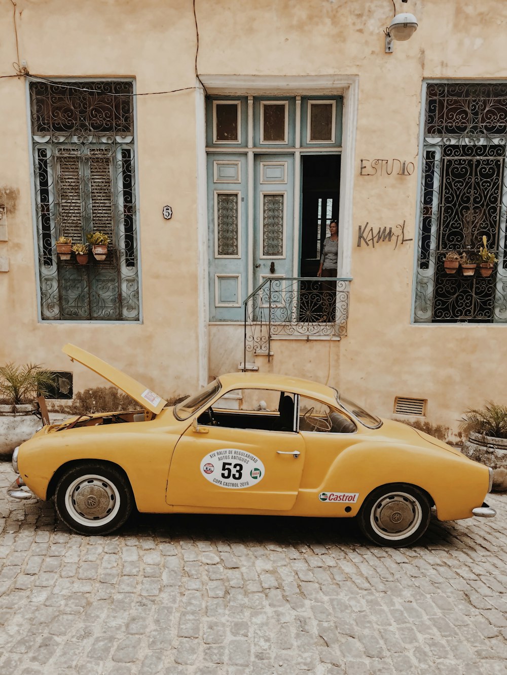 yellow volkswagen beetle parked beside white concrete building during daytime