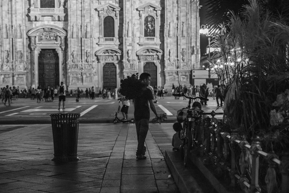 grayscale photo of people walking on sidewalk near building