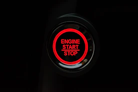 Hand pressing a red button on a mobile app to remotely block a vehicle