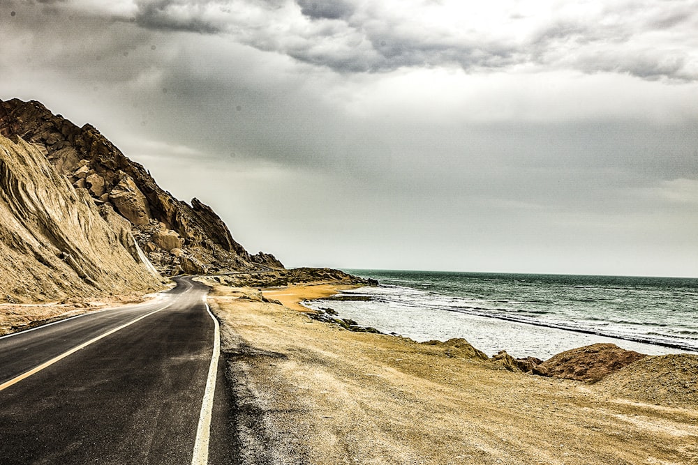 gray concrete road beside body of water during daytime