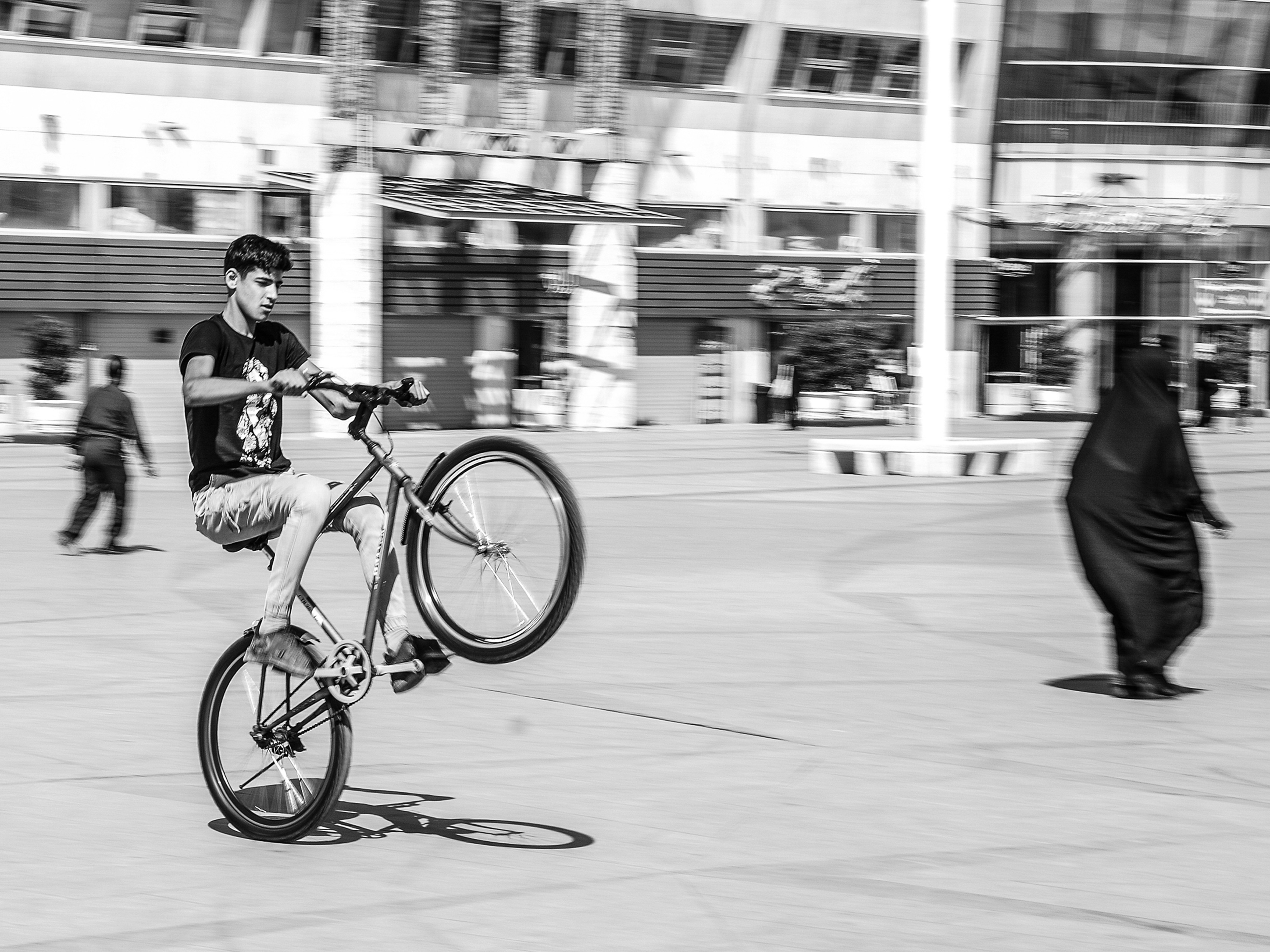 grayscale photo of man riding bicycle