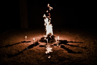 A small fire circle at dusk, around which people gather in quiet reflection.