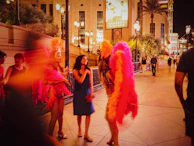 Nighttime scene of a street filled with swirling dancers in magenta and yellow costumes.