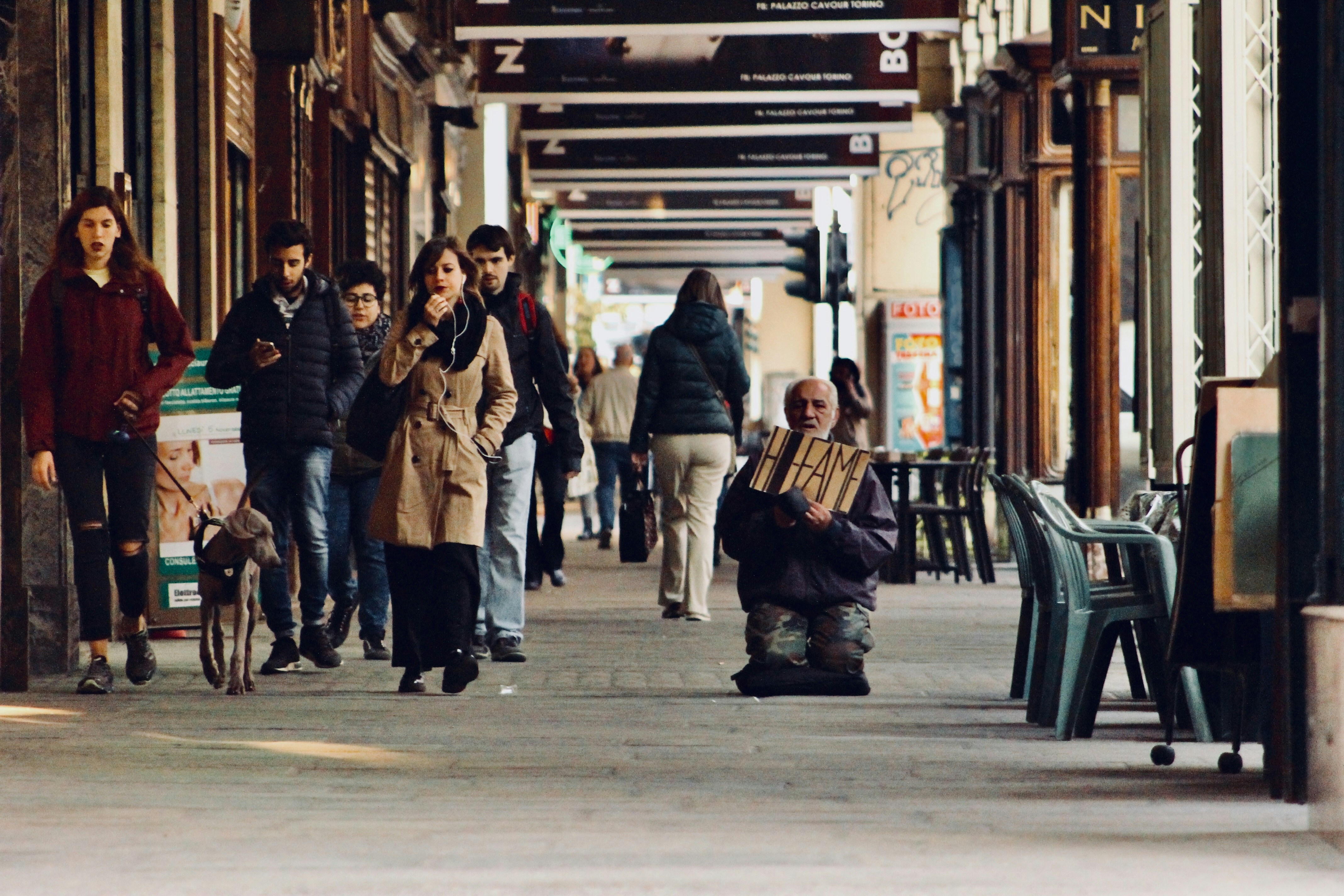 A person smiling and waving at a group of strangers on the street.