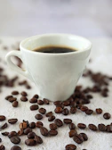 Minimalist coffee setup featuring a steaming cup, beans, and subtle topographic lines on a cream background