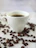 Man savoring a freshly brewed cup of coffee at a minimalist wooden table with coffee beans scattered nearby.