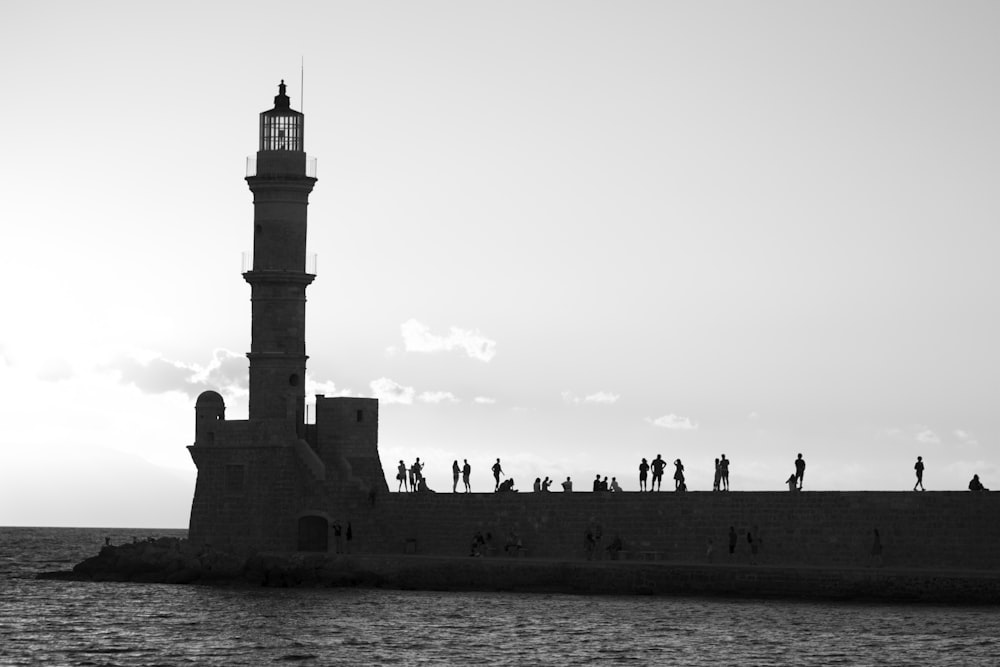 people walking on concrete bridge near lighthouse during daytime