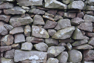 Close-up of a hand-crafted dry stone wall blending naturally with greenery.