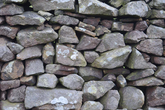 Close-up of a hand-crafted dry stone wall blending naturally with greenery.