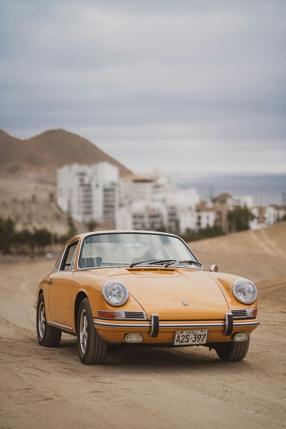 yellow porsche 911 parked on brown field during daytime