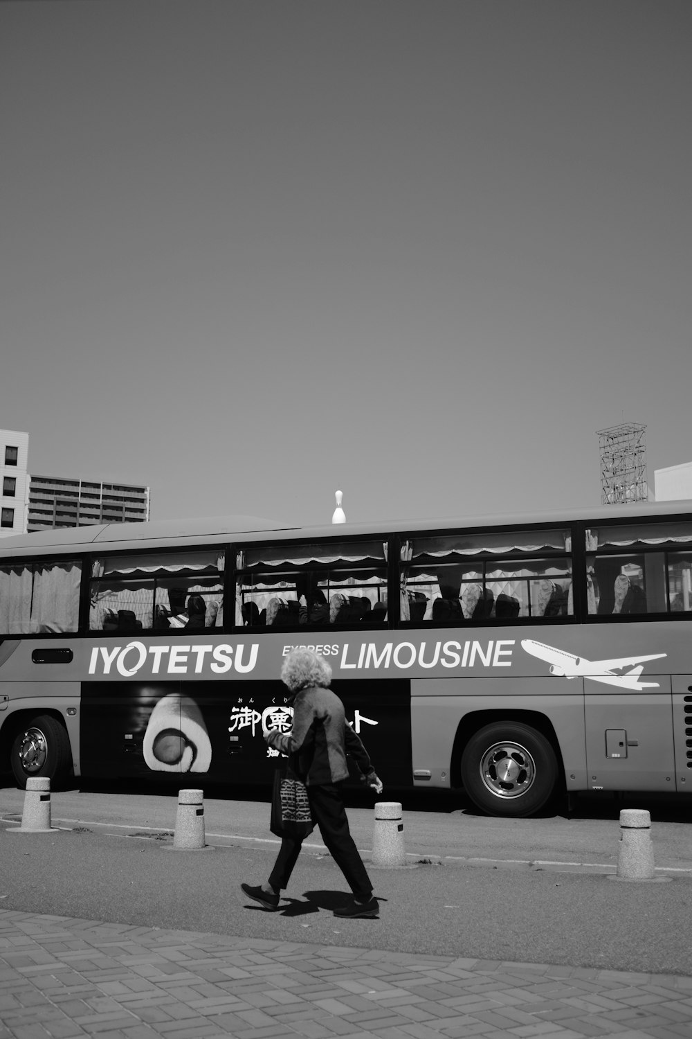 grayscale photo of man and woman standing beside bus