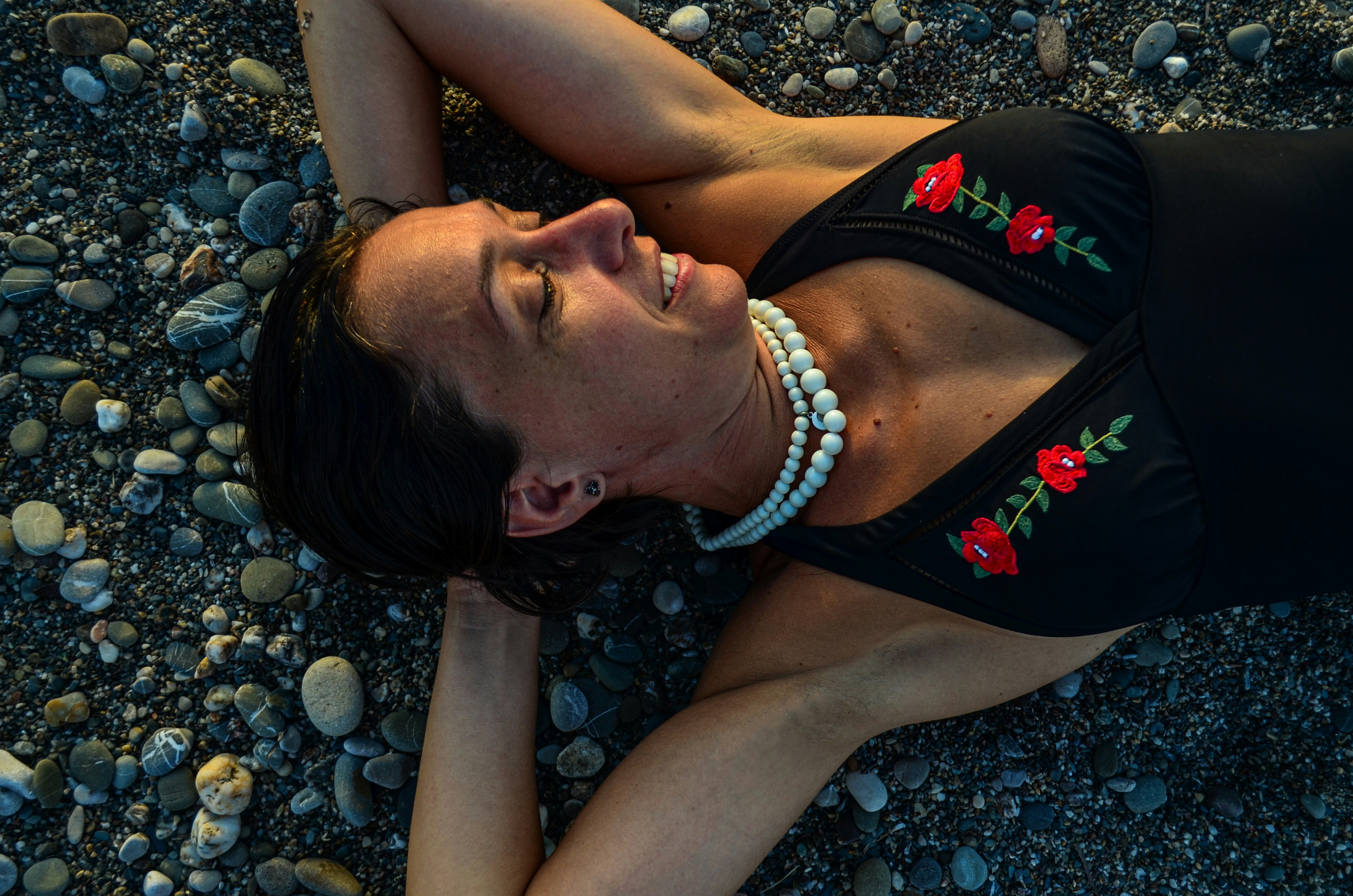 woman in black and red tank top lying on gray rocks