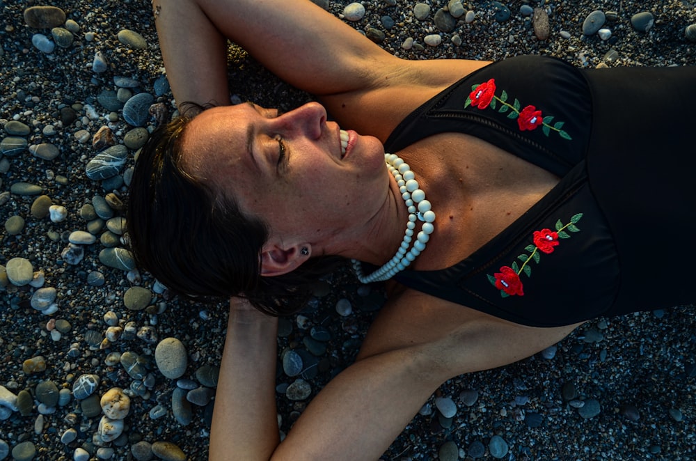woman in black and red tank top lying on gray rocks