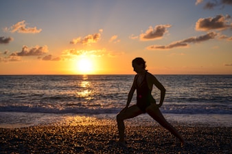 An energetic person stretching outdoors during sunrise