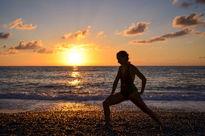 A relaxed man practicing gentle stretching outdoors at sunrise.