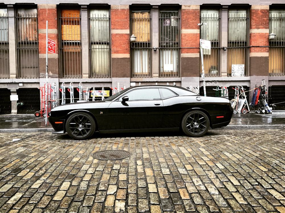 black coupe parked on sidewalk during daytime