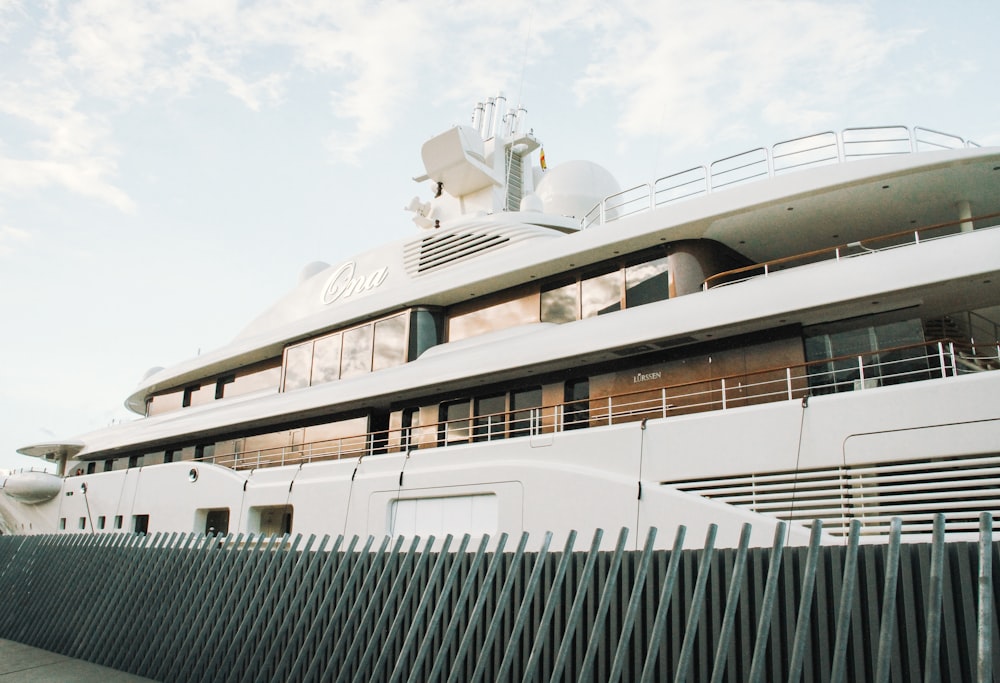 a large white boat sitting next to a black fence