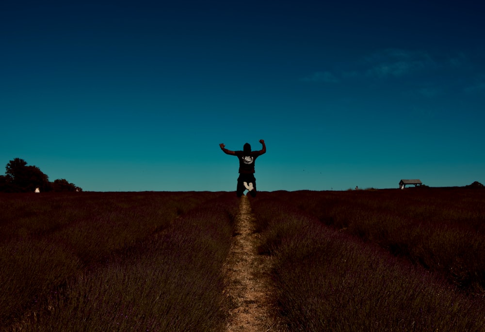 woman in black dress standing on brown grass field under blue sky during daytime