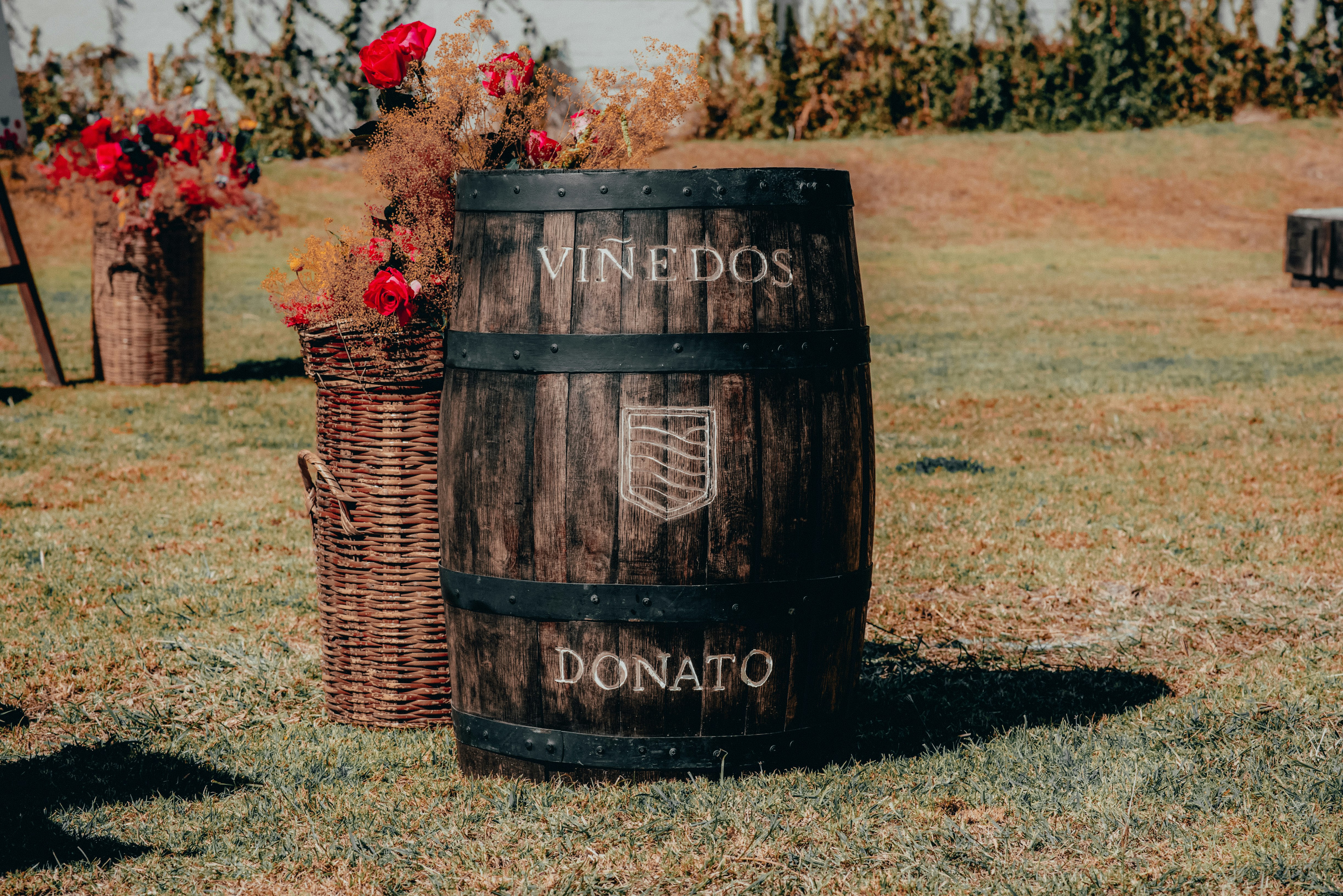 brown wooden barrel with red flowers on the ground