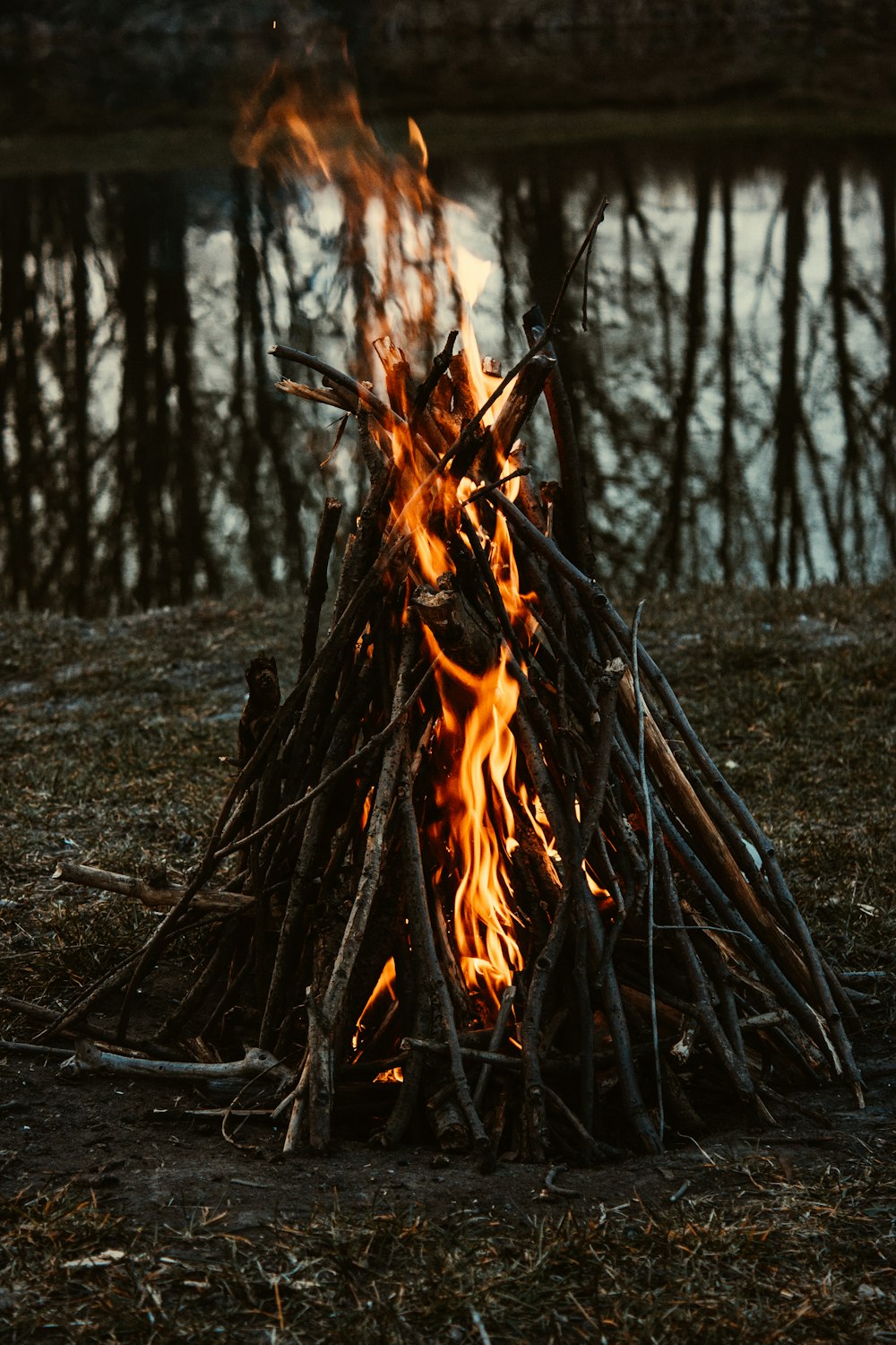 a campfire is lit in front of a body of water