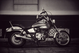 A classic cruiser motorcycle with chrome details resting beside a rustic wooden fence.