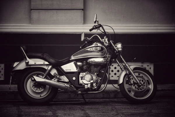 A classic cruiser motorcycle with chrome details resting beside a rustic wooden fence.