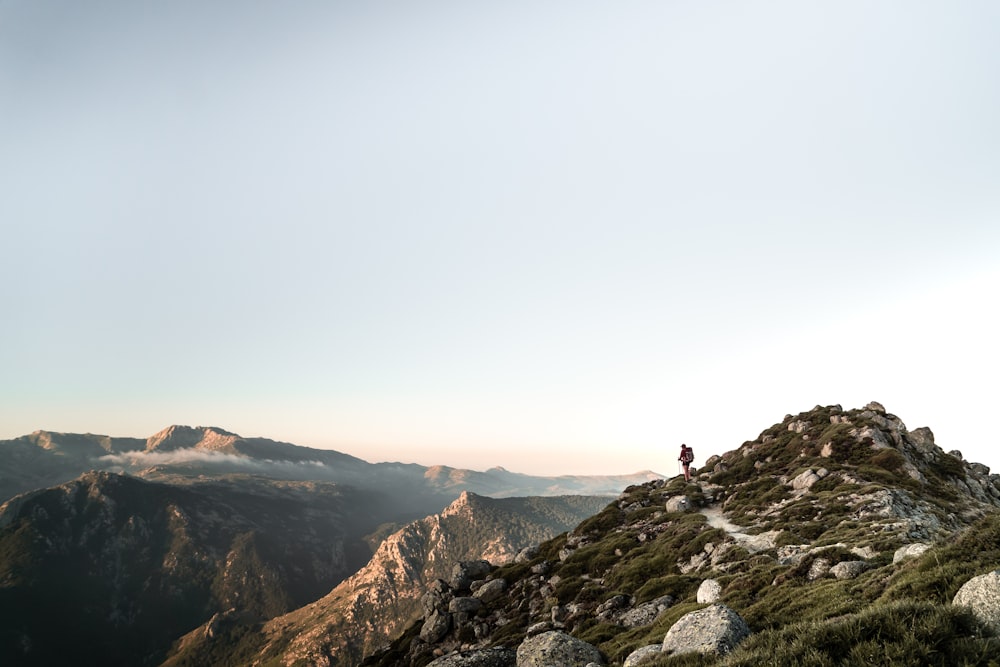 person standing on rocky mountain during daytime