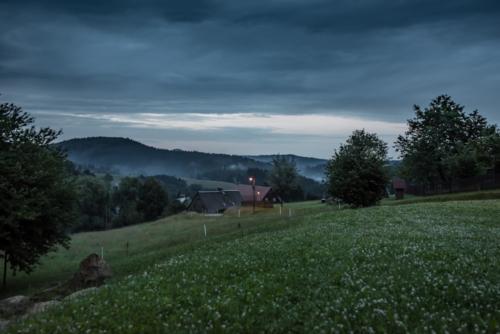 green grass field near house under cloudy sky during daytime