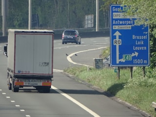 A comfortable taxi driving along a scenic highway between Lille and Brussels under a clear sky.